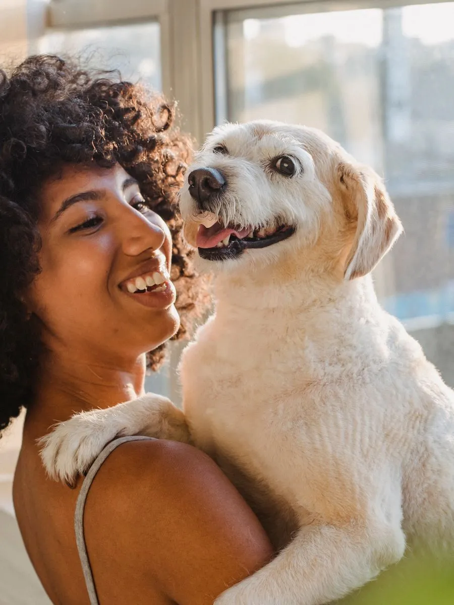 Una mujer sonríe mientras abraza a su perro